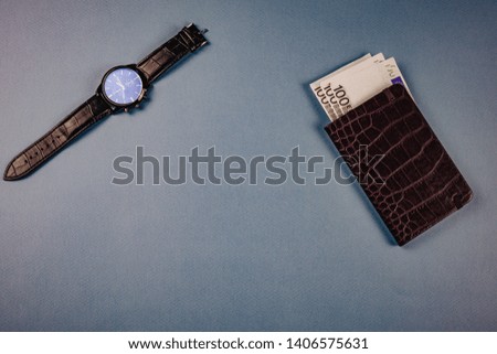 clock and wallet with money lying on a blue background