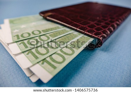 money in a leather wallet on a blue background.