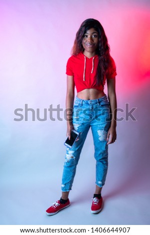 Hip young black woman in red shirt and jeans in the studio. African American Lifestyle concept.