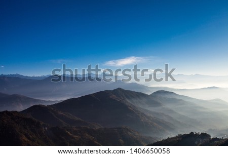Sunrise. Early morning in Himalaya mountains. Mist-shrouded mountain peaks. Bright blinding sun. Blue sky. Fog. Mountains landscape. Highlands nature. Backgrounds. Nepal. Royalty-Free Stock Photo #1406650058