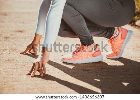 Photo of fit girl with pink sneakers in start position for running. Healthy lifestyle