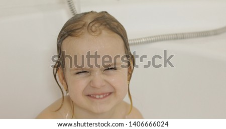 Attractive three years old girl takes a bath. Wet hair with bath foam. Cute blonde child. Brown eyes. Pretty little child, 3-4 year old blonde girl in bathroom