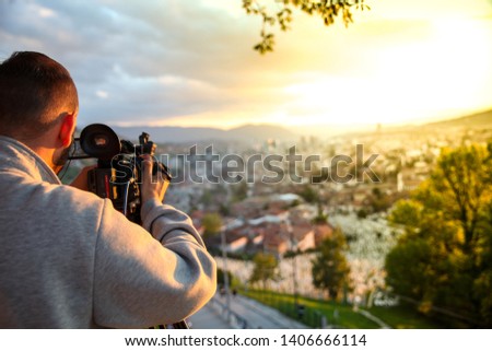 video camera, cameraman, sunset. The photographer records the sunset in the background of a beautiful city.-Image