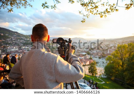 video camera, cameraman, sunset. The photographer records the sunset in the background of a beautiful city.-Image