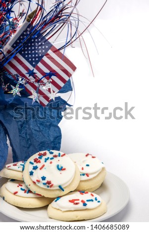 red white and blue patriotic frosted sugar cookies on a white plate with flag and mylar sparkly decor in the background in vertical orientation