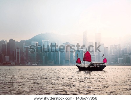 Junk Boat in Hong Kong harbor with cityscape under fog in background