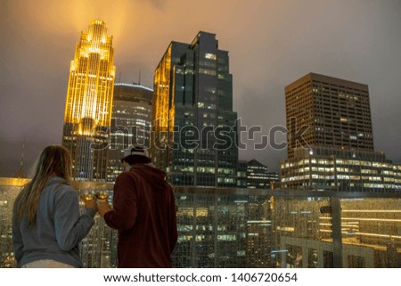 Young Couple relaxes on the rooftop Patio of a Downtown Minneapolis Skyscraper with a view of the Skyline behind