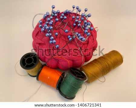 Pins on red cushion and 4 rolls of threads Royalty-Free Stock Photo #1406721341