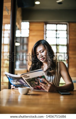 Beautiful woman reading magazine in cafe