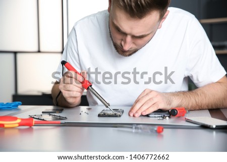 Technician repairing mobile phone at table in workshop