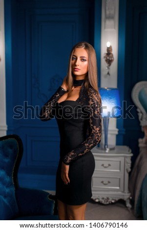 Beautiful young girl in black dress poses in classic interior