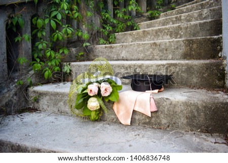 Graduation cap or mortaboard with a bunch of roses on the old stairs  in the graduation day. Education concept.