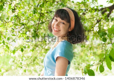 Beautiful woman in blue dress with blooming apple trees in spring garden