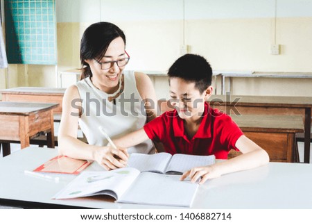 Teacher teaching boy to do homework in classroom
