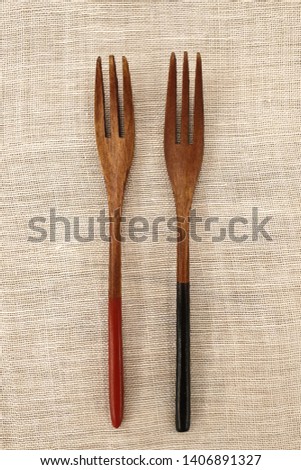 There are two wooden forks in the brown background.