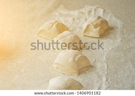 chopped raw kneaded dough into pieces on the table against the background of the kitchen interior. cooking baking dish.