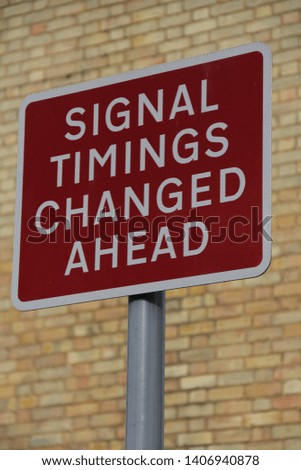 closeup sign timing signal changed ahead white on red background against brick wall