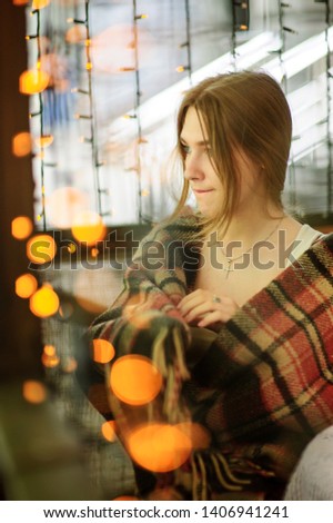 a very beautiful girl is sitting in a cafe, gazing straight ahead and beckoning to her charming look