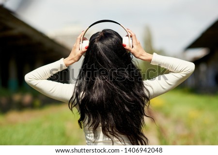 woman puts wireless headphones on her head and listening to music. Back view and space for text