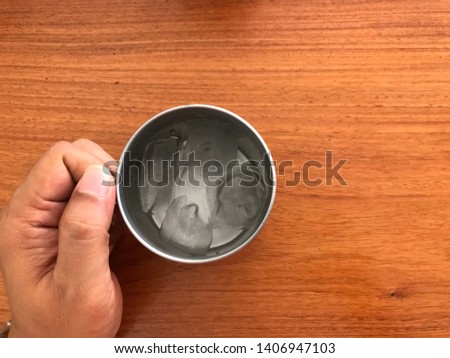 Ice in cup glass and hand holding on wooden table in restaurant on summer holiday vacation