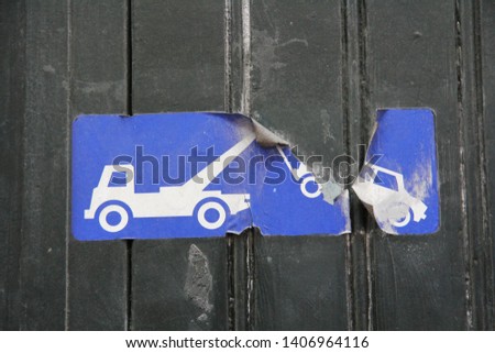 closeup of car tow away illegal parking sign in blue on black wooden garage door