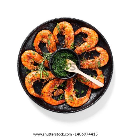 Grilled tiger shrimp with parsley sauce and lemon in black plate.isolated on white background