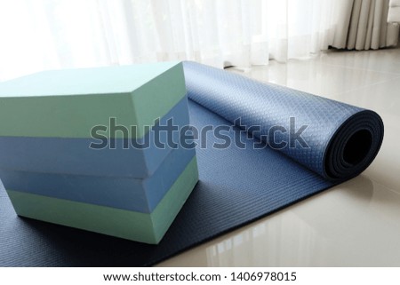 Accessories or props for yoga, pilates or fitness. two blocks, orange elastic band and navy yoga mat the floor.