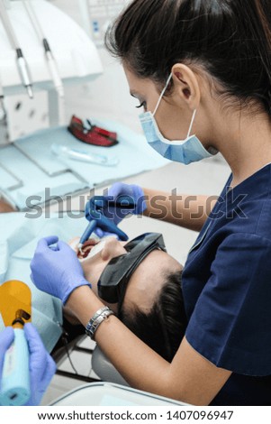 Girl dentist treats the patient. Doctor treats tooth pain at the dentist's office.