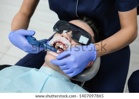 Girl dentist treats the patient. Doctor treats tooth pain at the dentist's office.