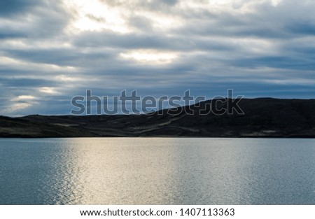 Fantastic view of Iceland in spring. Bright twilight of early white nights over the dreamy landscapes with blue water of the lake and green misty mountains. Splendid view from the lake house