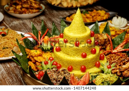 Nasi Tumpeng. Yellow rice in a cone shape. A festive Indonesian rice dish with side dishes. Royalty-Free Stock Photo #1407144248