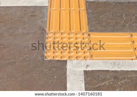 Bright yellow tactile paving for the visually impaired on the sidewalk.