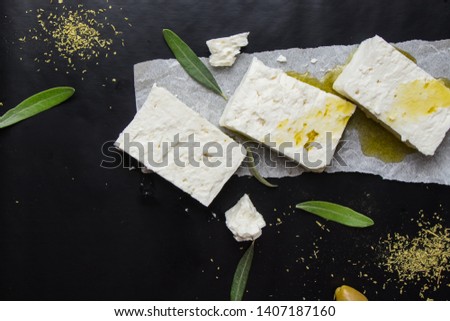 Feta Greek cheese with olives, oil and oregano on black background 