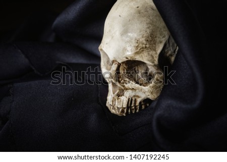 Close up photo an old skull covered in black robe