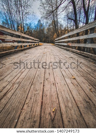 wide angle picture of a old wooden bridge across the river somewhere in Norway, mountains. Perfect postcard picture, Desaturated colours, bright sky, trees, forest blue sky,  wooden bridge, vintage.