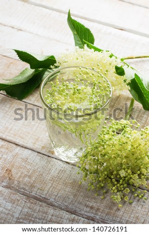 Refreshing sambucus juice in glass on wooden background. Selective focus.