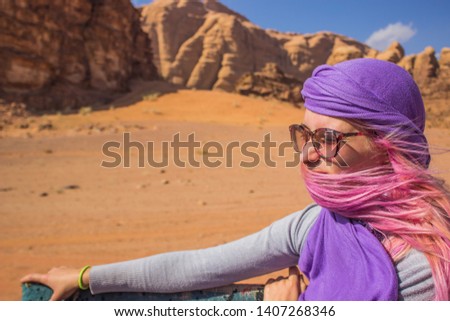 car tour through desert dunes and sand stone rocky background wilderness Middle East Wadi Rum famous touristic place concept picture of Caucasian girl portrait on speed with evolving hair on wind