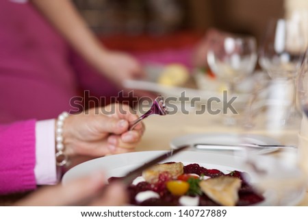 Closeup of senior woman holding fork and knife with dish on restaurant table