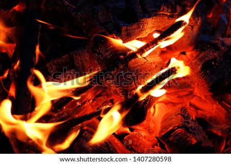 Glowing embers in hot red color, abstract background. The hot embers of burning wood log fire. Firewood burning on grill.