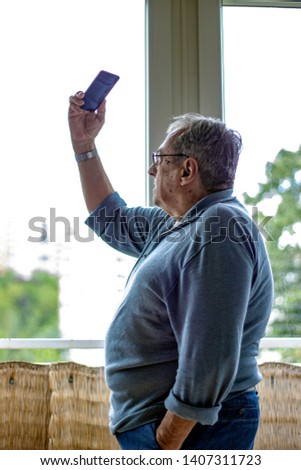 Keep your memories in your phone. Senior man taking a self picture. Close up. Focus on background. Senior man making selfie with smart phone. 