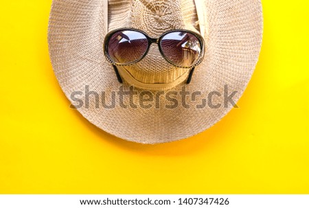 Beach hat with sunglasses on yellow background. Top view or flat lay. Summer concept.