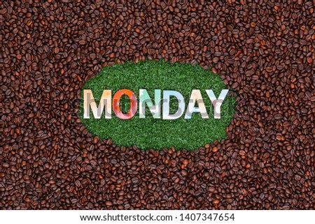 Monday written with colorful letters on artificial grass surrounded by roasted coffee beans