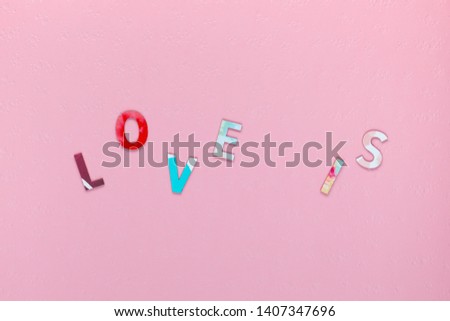 Inscription Love Is, randomly distributed on pink textured background, aligned in center