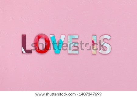 Inscription Love Is on pink textured background, shot close up