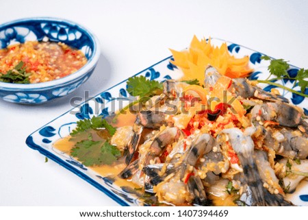 Raw Shrimps chilled in fish sauce on white dish with vegetable and red spicy sauce Viet food. They are decorated on white background 