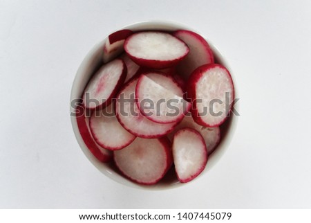 Photograph of a background with sliced ​​radish pieces in a glass bowl on a white background. Food photo. Top view