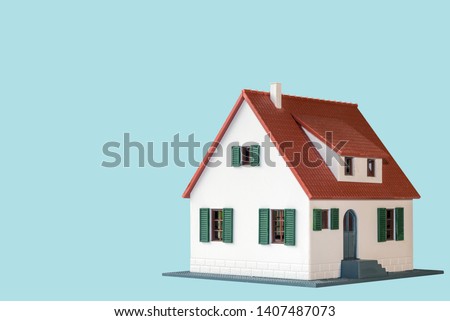 Model of house painted white under the tiled roof isolated on the blue background. Royalty-Free Stock Photo #1407487073