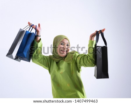 malay women with tudung holding shopping bags on the gray background