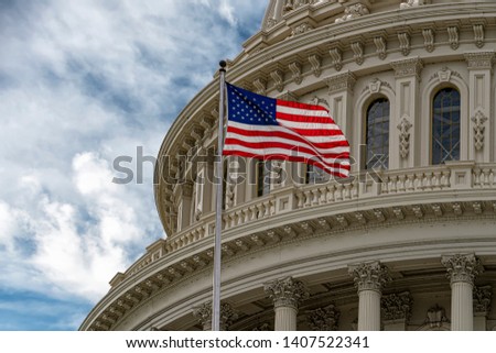 Washington DC Capitol with waving flag on cloudy day Royalty-Free Stock Photo #1407522341