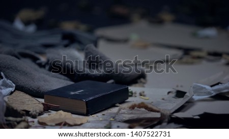 Bible lying on floor in dirty place full of garbage, hope and belief concept